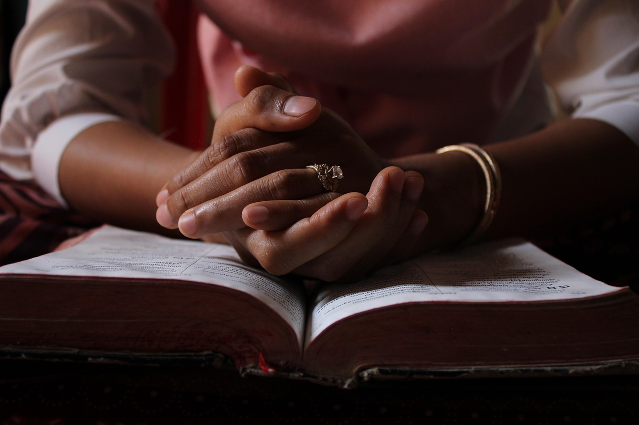 Pessoa em oração com as mãos unidas