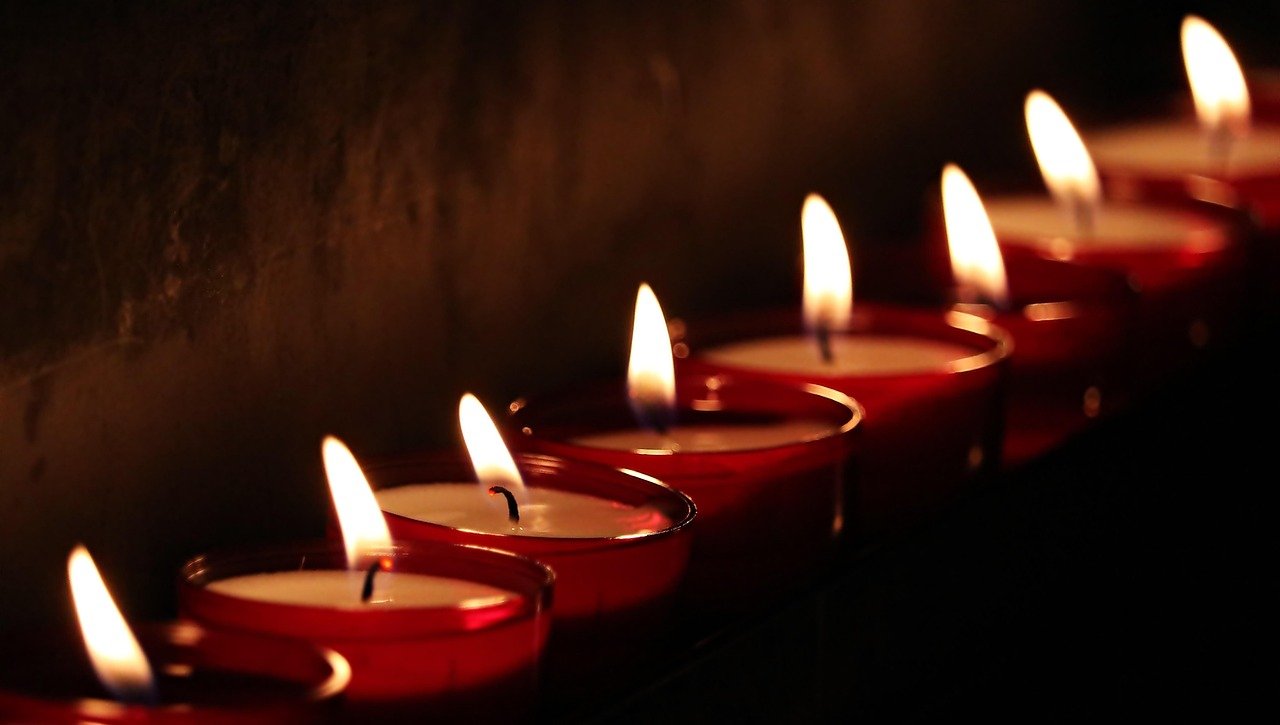Bíblia aberta sobre mesa de madeira com vela acesa e luz acolhedora no quarto