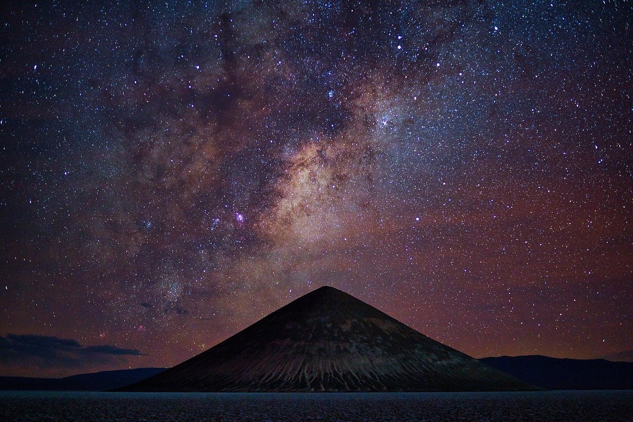 Céu noturno estrelado majestoso com a Via Láctea sobre montanhas e luz serena