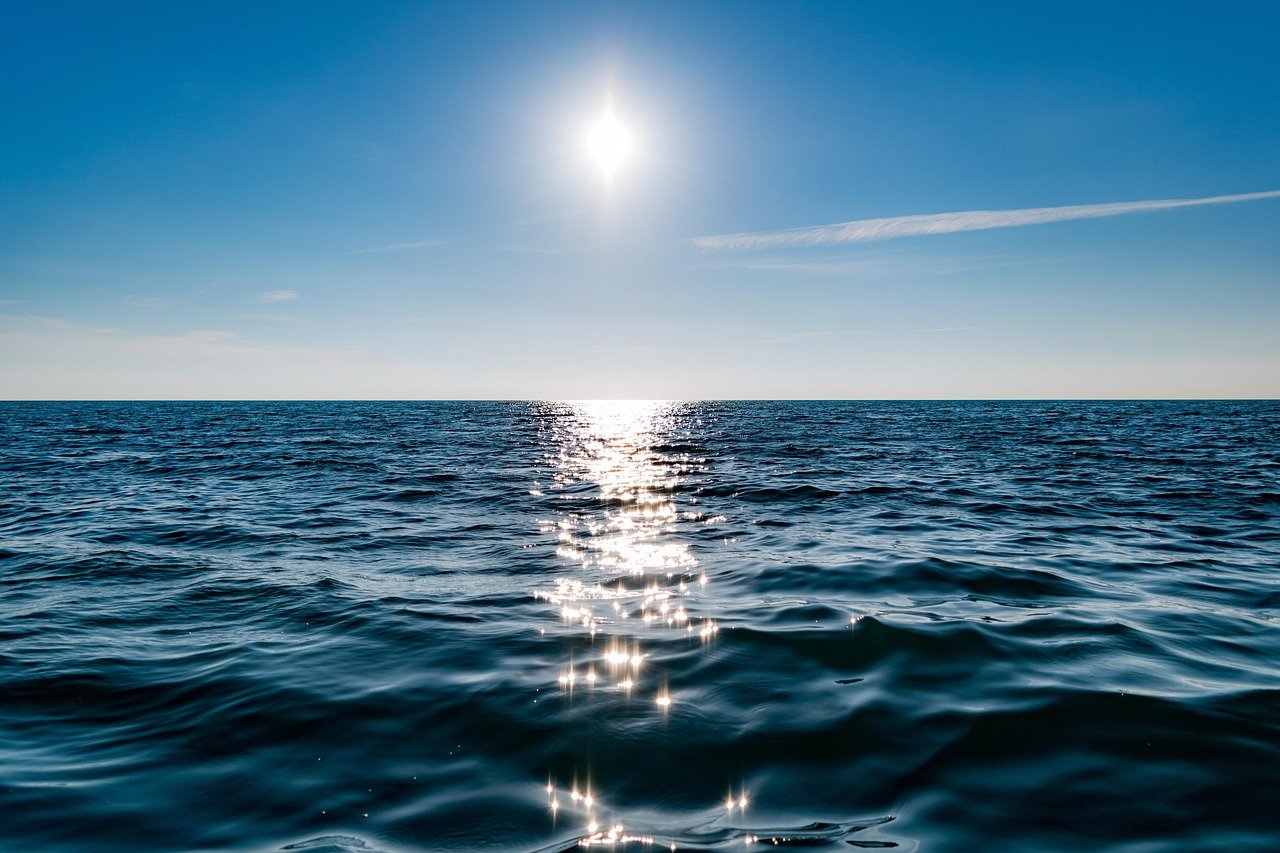 Céu limpo com raios de sol refletindo sobre águas calmas e profundas