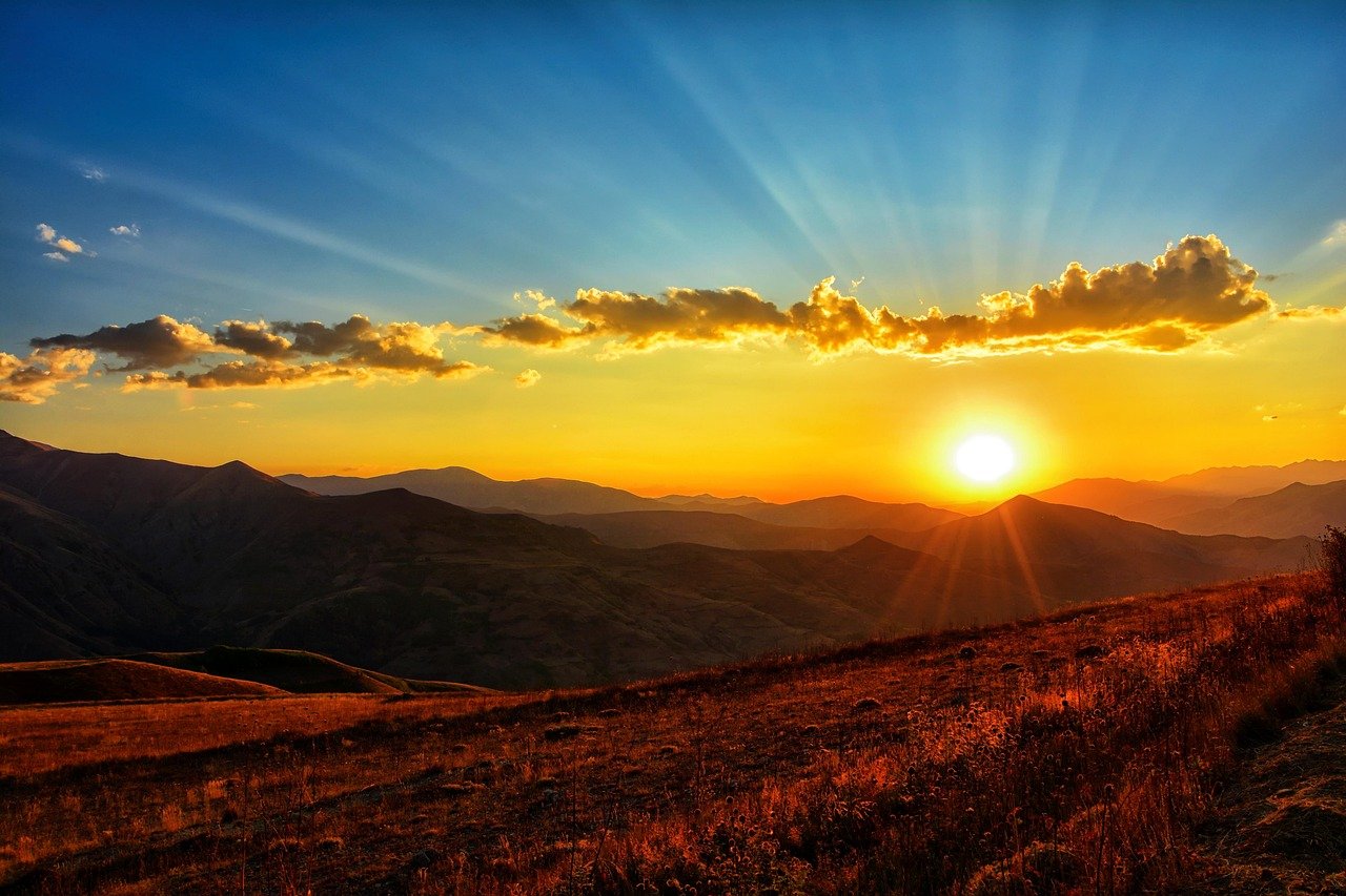 Pôr do sol majestoso com raios iluminando o horizonte de montanhas