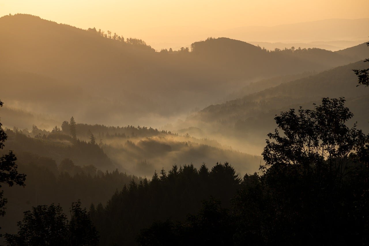 Raios de sol da alvorada rompendo nuvens matinais sobre colinas tranquilas