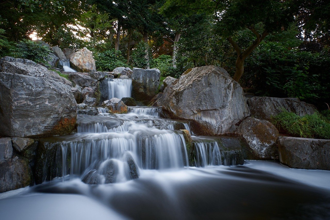Cachoeira cristalina descendo entre pedras cobertas de musgo em floresta verdejante